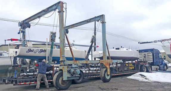 Truck transporting boats at a dockyard.