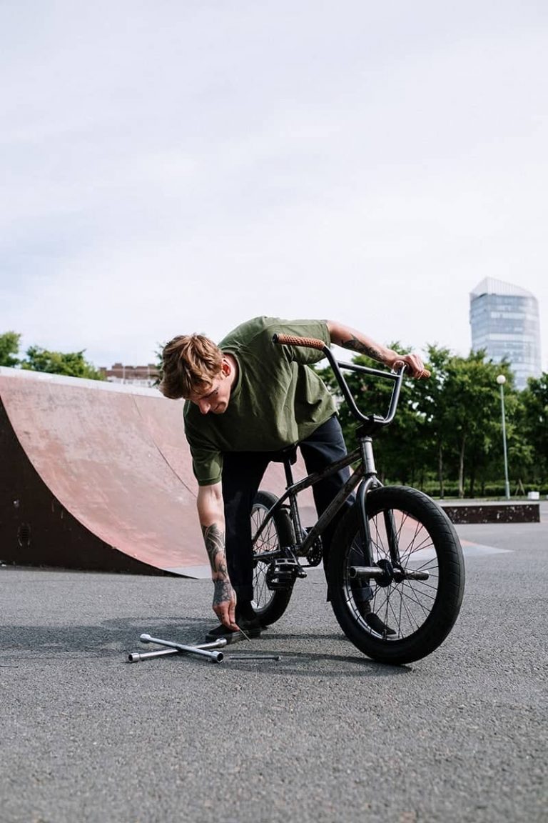 Person adjusting a BMX bike at a skate park.