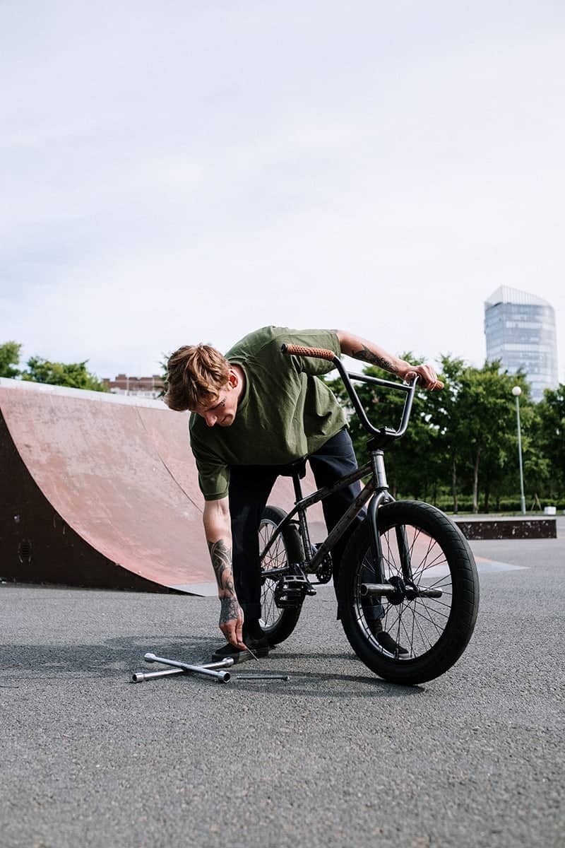 Person adjusting a BMX bike at a skate park.