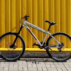 A sleek silver mountain bike against a vibrant yellow wall.