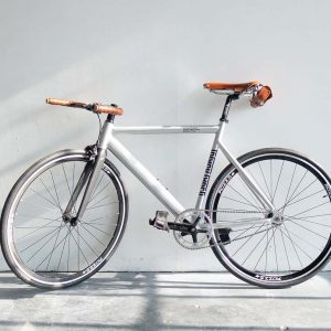Minimalist white fixed-gear bicycle with brown leather accents.