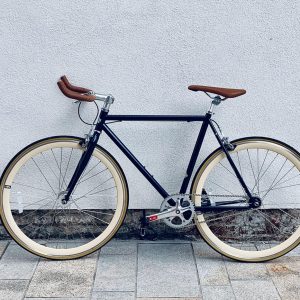 A sleek black bicycle with tan tires and brown leather accents.