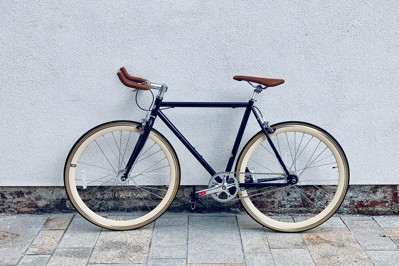 A sleek black bicycle with tan tires and brown leather accents.
