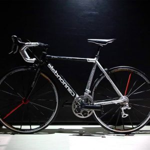 A sleek black and white road bike with drop handlebars against a dark background.