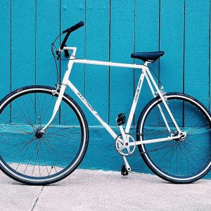 A sleek white bicycle against a vibrant blue wall.