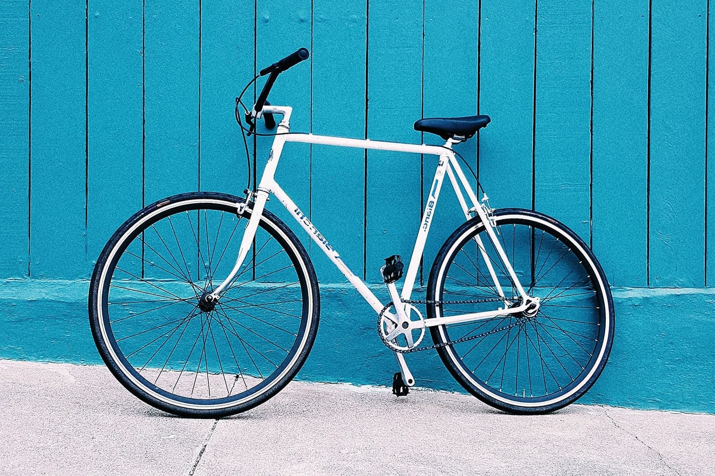 A sleek white bicycle against a vibrant blue wall.