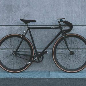 A sleek black road bike against a concrete wall.