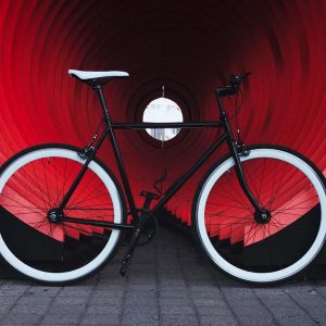 Black bicycle with white tires inside a red tunnel.