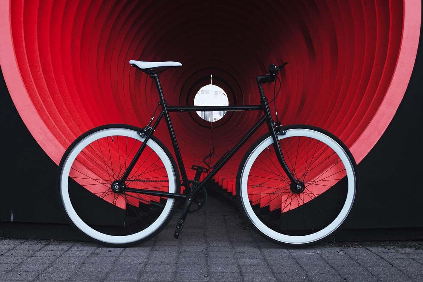 Black bicycle with white tires inside a red tunnel.