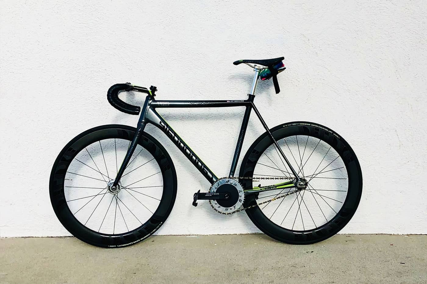 Sleek black and silver bicycle with deep-section wheels against a white wall.