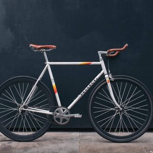 A stylish white fixed-gear bicycle with brown leather handlebars and saddle.