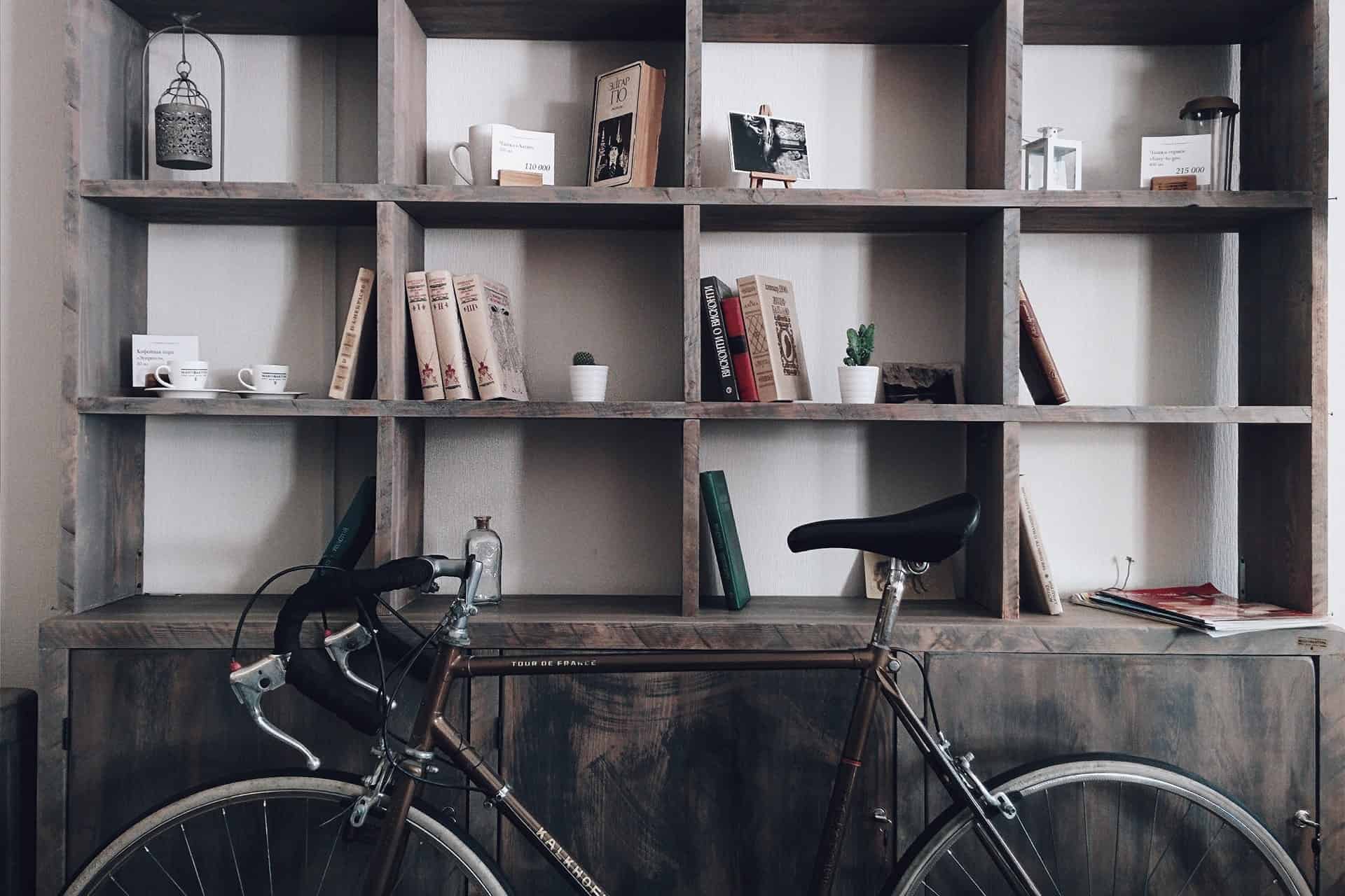 A bicycle parked in front of a bookshelf filled with books and decor.