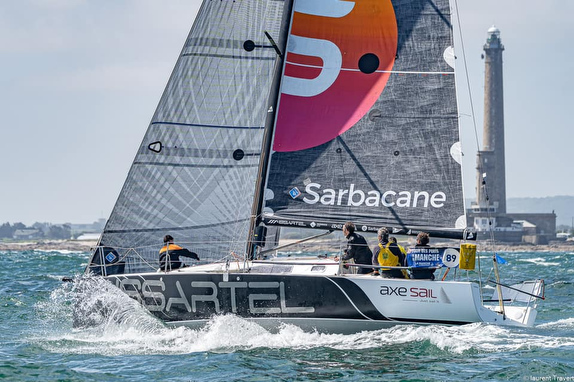 Sailboat racing near a coastal lighthouse.