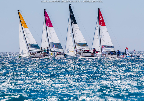 Sailboats racing on sparkling blue water.