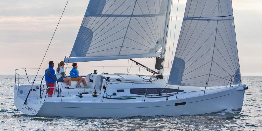 A person sailing a white sailboat on calm waters under clear skies.