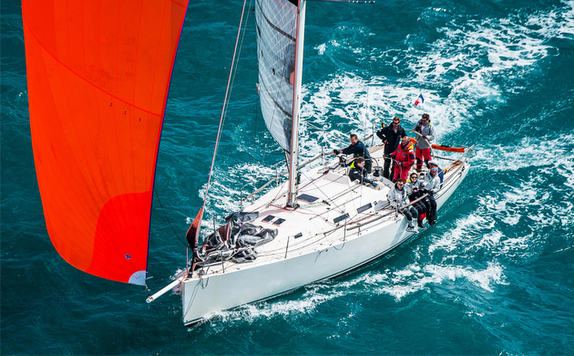 Sailboat with orange sail in ocean.