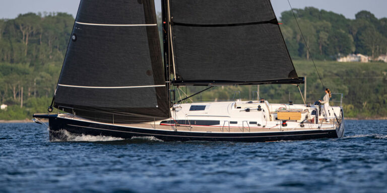 Sailboat with black sails on water.
