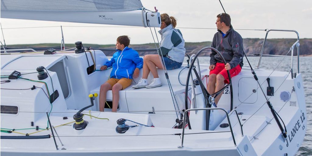 Three people sailing on a white yacht, enjoying the breeze.