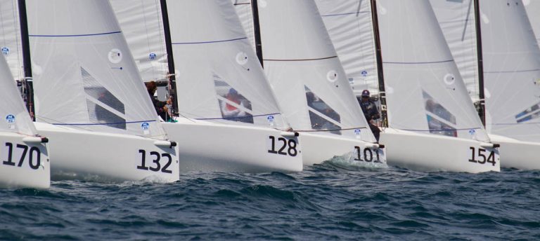 Sailboats with numbers 32, 128, and 107 racing on the water.