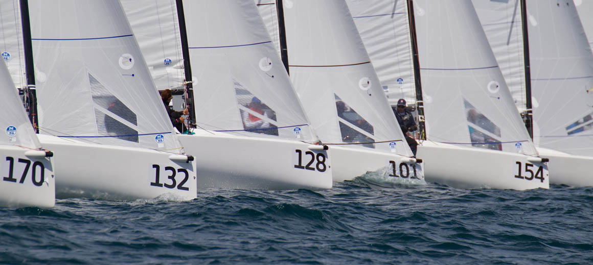 Sailboats with numbers 32, 128, and 107 racing on the water.