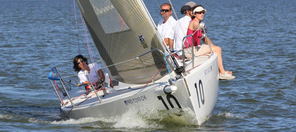 Sailboat number 10 racing with crew on board in sunny weather.