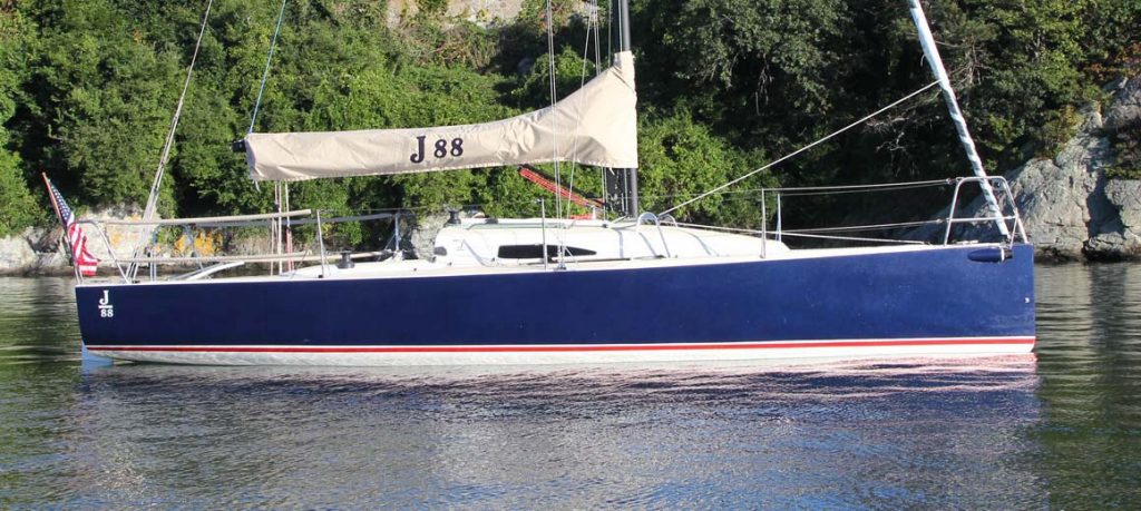 A sleek blue sailboat docked by the shore on a calm day.