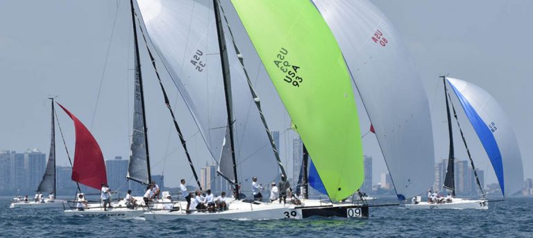 Sailboats racing with colorful spinnakers in the wind on a clear day.
