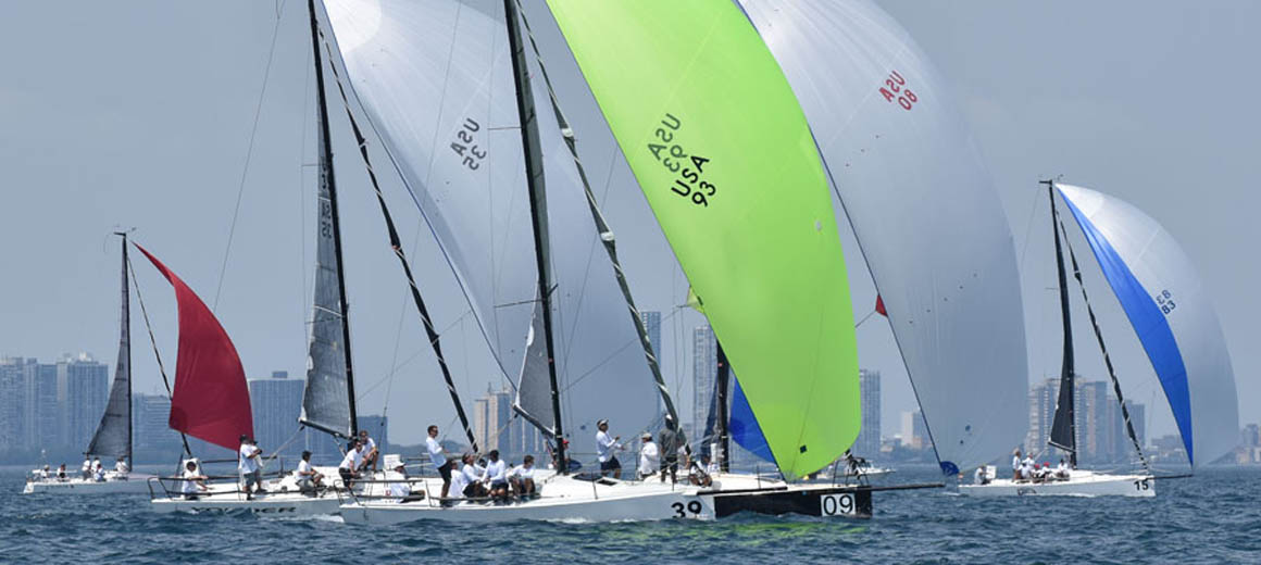 Sailboats racing with colorful spinnakers in the wind on a clear day.