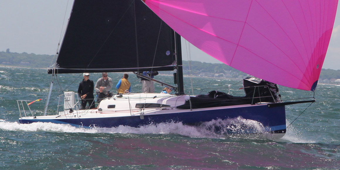 Sailboat with a vibrant pink sail gliding through choppy waters.