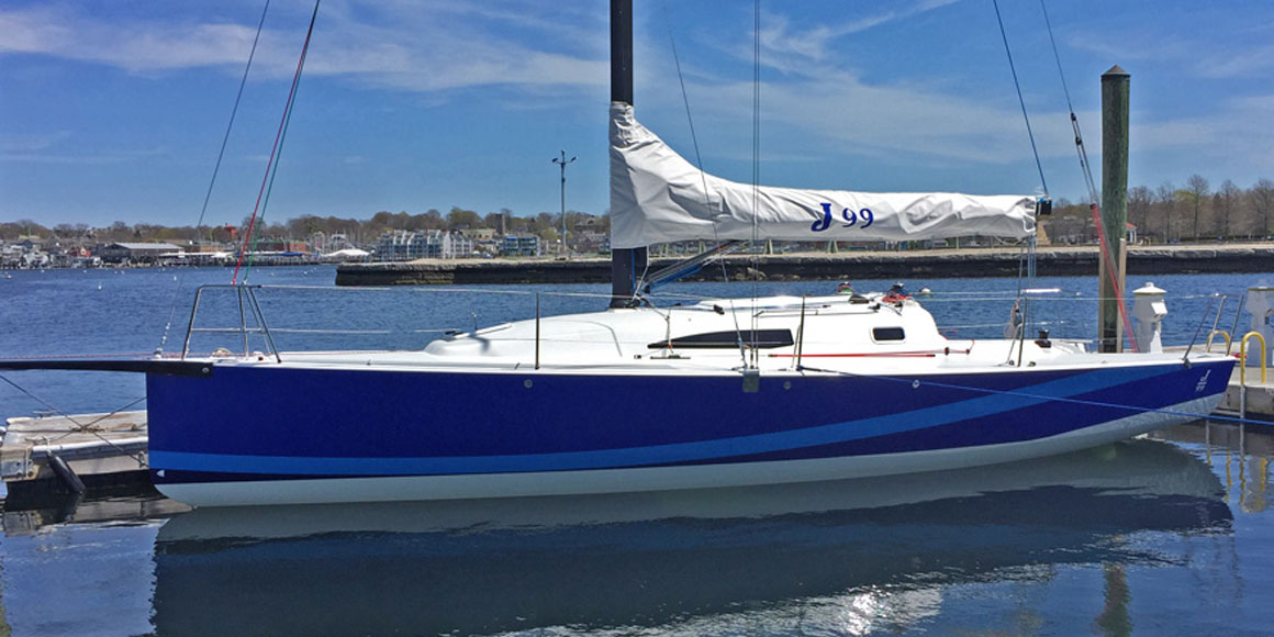 A blue and white sailboat docked in calm water under a clear sky.