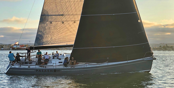 Sailboat with people on calm water.