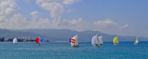 Sailboats with colorful sails on ocean.