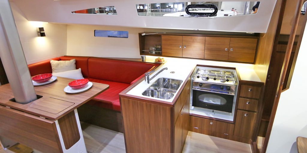 Compact RV kitchen with red cushioned seating and modern appliances.