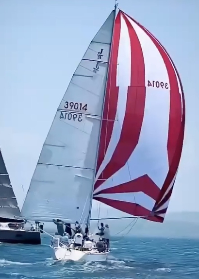 Sailboat with red and white spinnaker sailing.