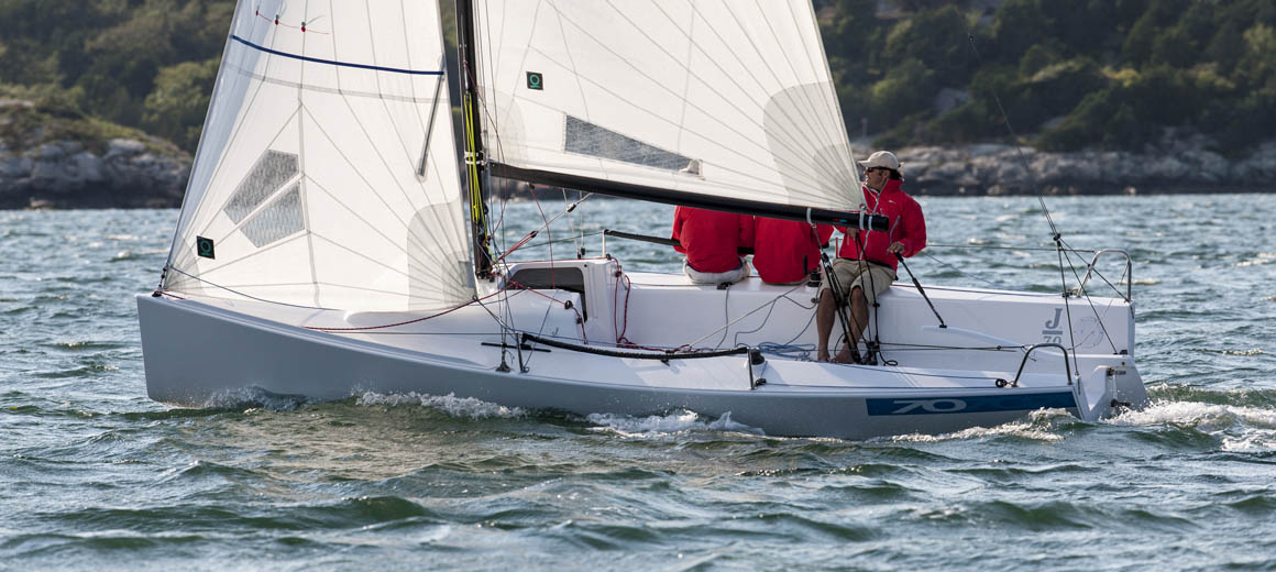 Sailor steering a small sailboat on a breezy day.