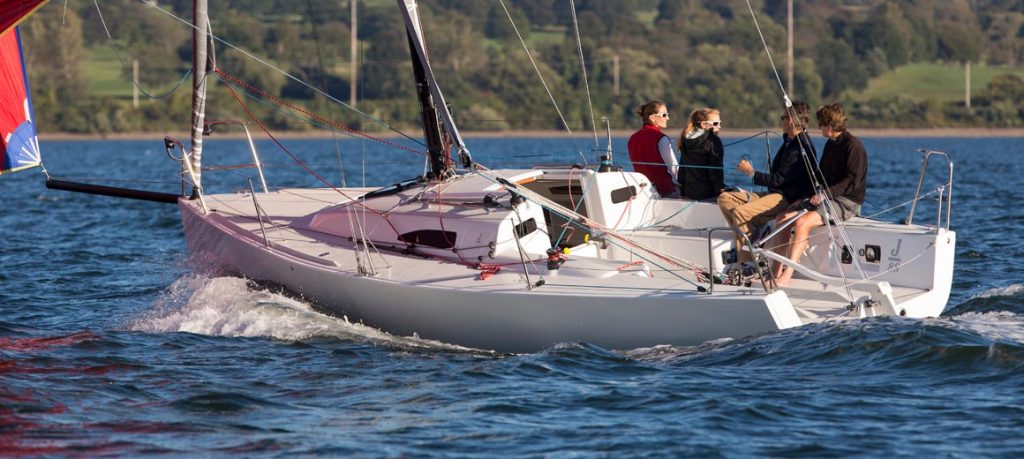 Two people sailing on a small sailboat in calm waters.