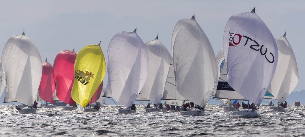 Colorful sailboats racing on a windy day over choppy water.