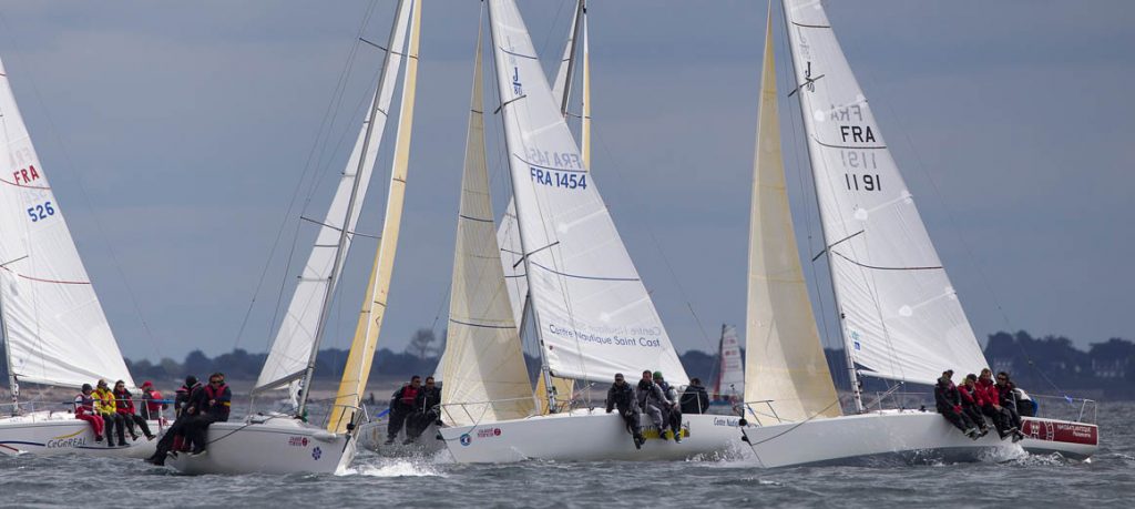 Sailboats racing on choppy waters under a cloudy sky.