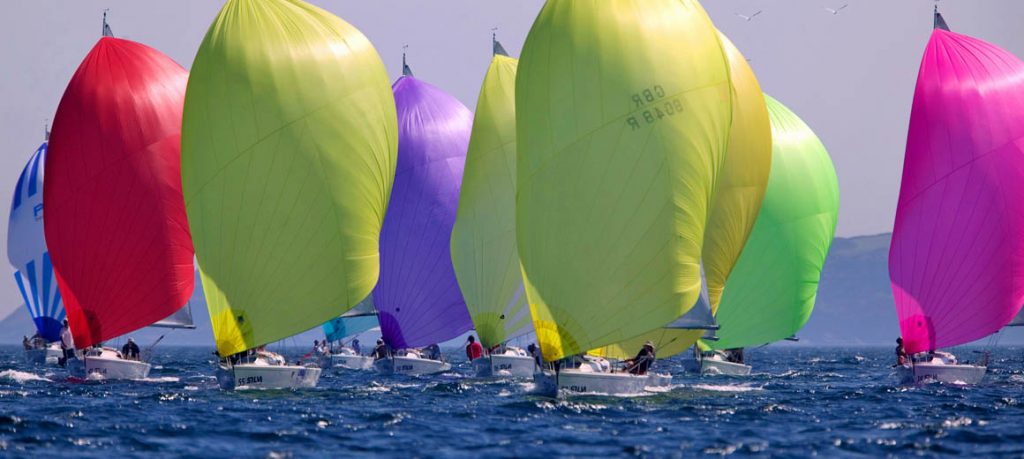 Colorful sailboats racing on the ocean with vibrant spinnakers.