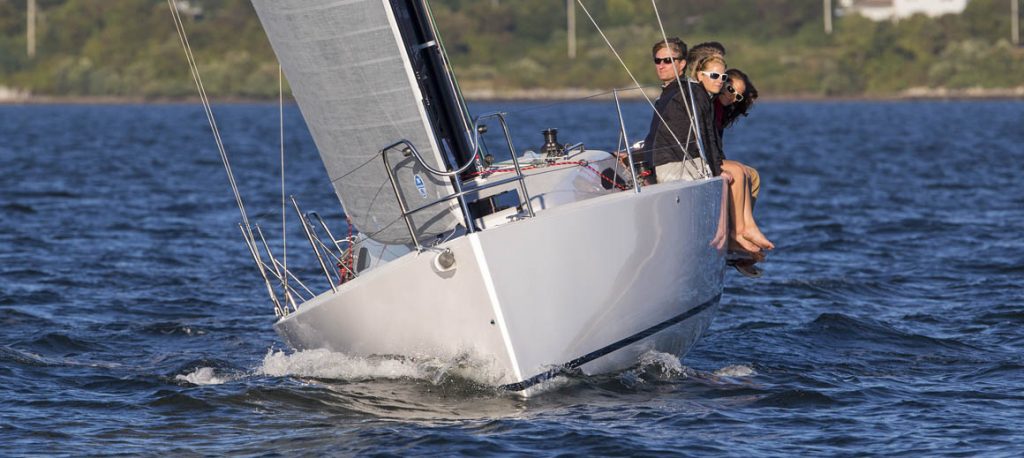 A white sailboat cutting through the water with people onboard.