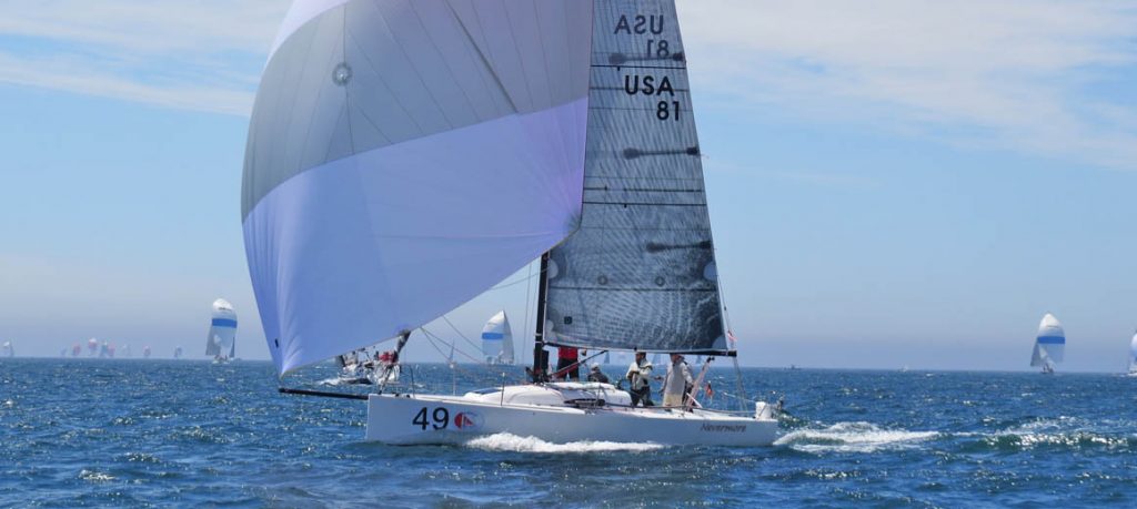 Sailboat racing on a sunny day with a vibrant blue spinnaker.