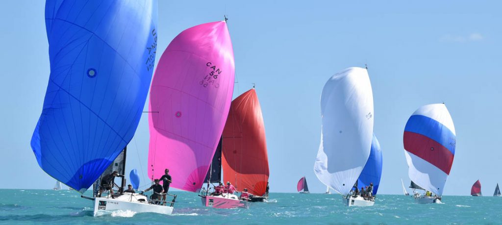 Colorful sailboats racing on a clear, sunny day.