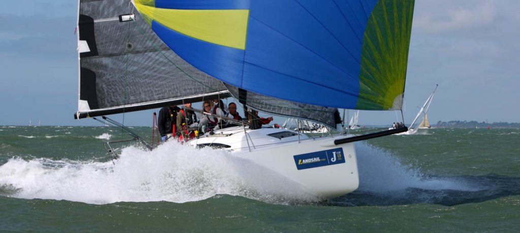 Sailboat racing with vibrant spinnaker on choppy waters.