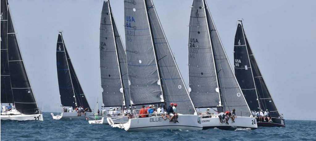 Sailboats racing on the water with crew members managing sails.