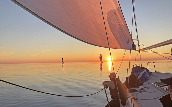 Sailing at sunset with calm waters.
