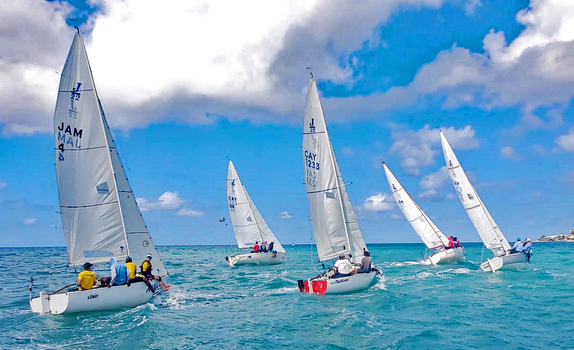 Sailboats racing on clear blue ocean.
