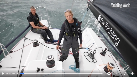 Two sailors on a yacht deck sailing.