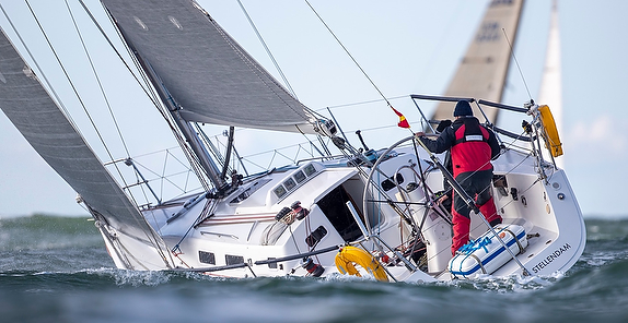 Sailboat tilting on rough ocean waters.