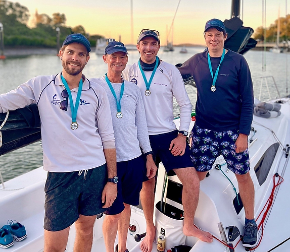 Four men on a boat wearing medals.