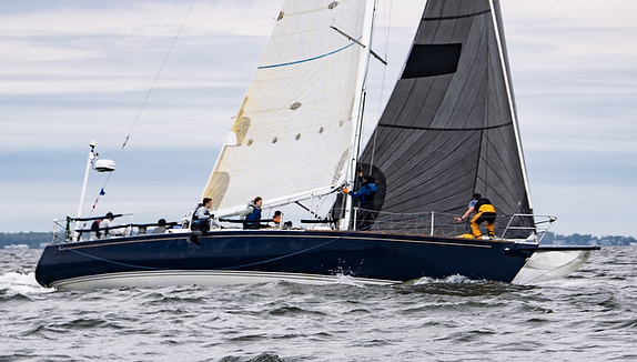 Sailboat with crew navigating through water.